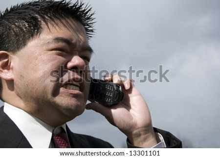 Angry asian man talking on cell phone
