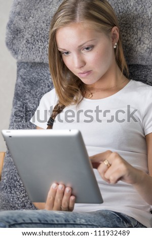 Beautiful girl relaxing at home, surfing the internet and looking at the screen of a touchpad