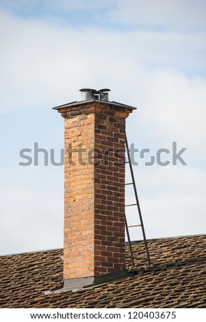 Building exterior with vintage clay chimney and tiled rooftop set against blue sky on a sunny day