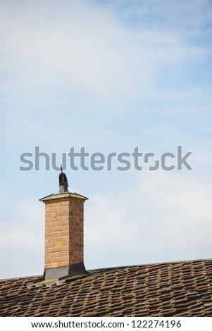 Building exterior with vintage clay chimney and tiled rooftop set against blue sky on a sunny day