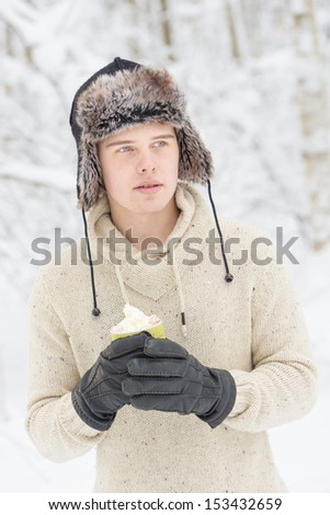 Christmas scene with natural looking teenage male outdoors in snow covered winter landscape.