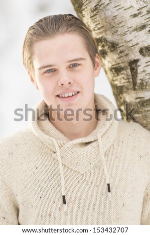Christmas scene with natural looking teenage male outdoors in snow covered winter landscape.