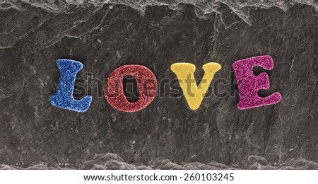 The word love in colorful letters on black stone background. Conceptual image of love and romance.