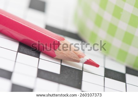 Closeup of crossword puzzle and red pencil. Conceptual image of problem solving, finding solutions and intelligence.