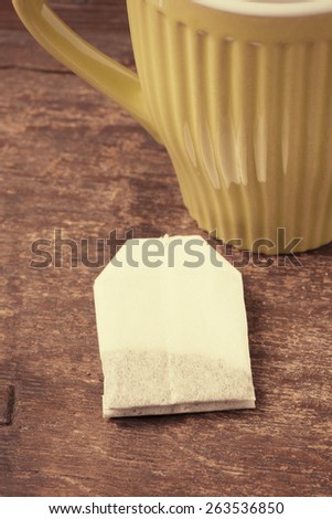 Closeup of wooden table with  a teacup and a teabag. Food and drink backdrop showing a mug of hot beverage served.