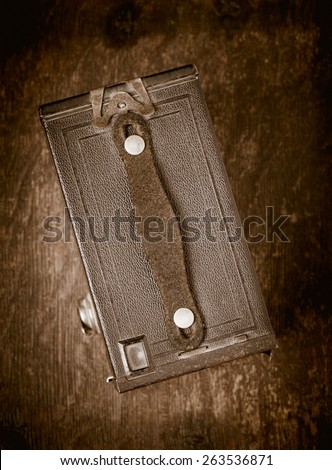 Top view of old retro film camera lying on wooden table. Photographic nostalgia with old-fashioned photo equipment. Conceptual image of old technology with a vintage look.