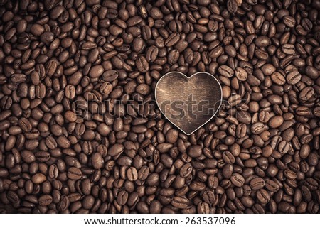 Closeup of dark roasted coffee beans and a heart. Food and drink backdrop showing aromatic and beautiful coffee beans with copy space.