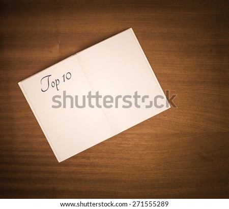 Open book on wooden table with blank white pages and the title top ten.