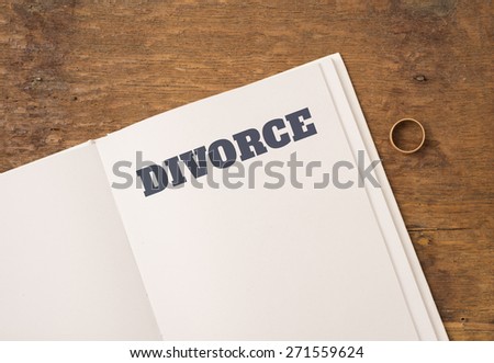 Book with title Divorce and blank white page. One wedding ring on the side. Empty space for copy. Conceptual image of divorce.