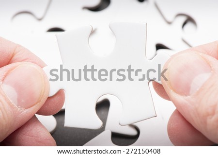 Hand holding puzzle piece. Conceptual image of connection, solution and business strategy.