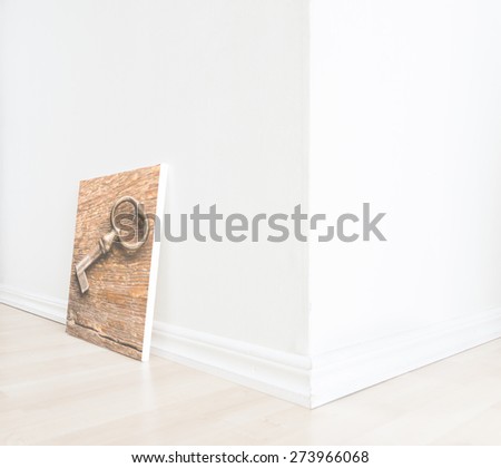 Empty room interior with artwork picture frame standing on wooden floor. Bright white scandinavian design and clean contemporary architecture. The room works as backdrop for a new office or a gallery.
