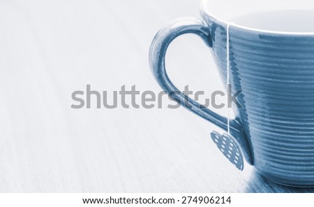 Closeup of a cup of tea with a heart shaped teabag on rustic wooden table. Food and drink backdrop showing a mug of hot beverage served. It can be used as a conceptual image for breakfast time.