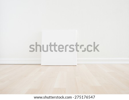 Empty room interior with blank artwork picture frame standing on wooden floor. Bright white scandinavian design and clean contemporary architecture. The room works as backdrop for a new home.