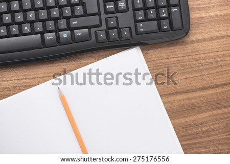 Office equipment at workplace. Desktop with keyboard and empty notebook. Conceptual image of desk work, communication technology and business.