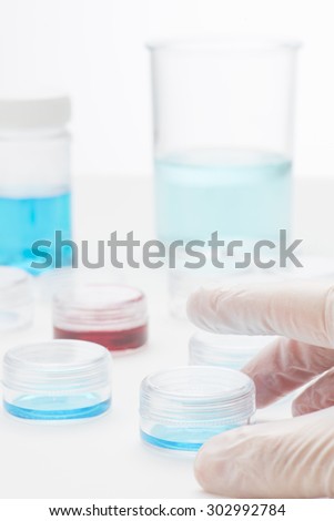 Hand of scientist working with fluids in lab. Conceptual image of clinical testing, scientific analysis and health science.