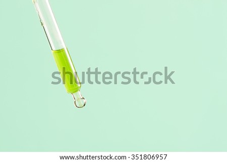 Medical or scientific dropper with green liquid. Concept of science research, healthcare and laboratory tests.