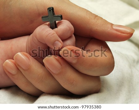 Christian baby holding a cross in his hand as symbol of faith