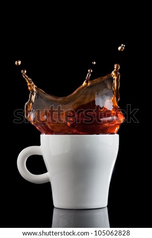 Splash of coffee in white cup isolated on black background