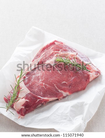 raw steak on white paper and herbs