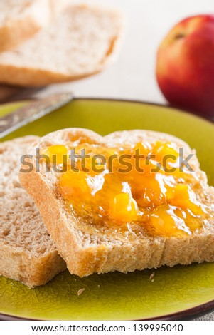 Spelt bread slices on a dish with peach marmalade close-up