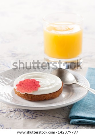 Lovely dessert with cream cake decorated with a pink flower and an orange juice