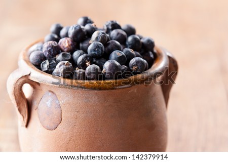 Pile of juniper berries on ceramic bowl close-up