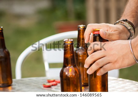 Hand opening a beer bottle in a terrace outdoors