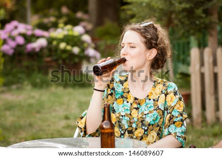 Beautiful young woman drinking beer in a terrace outdoors