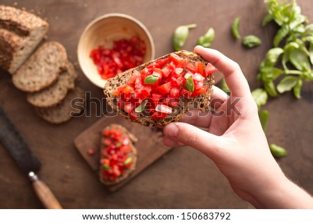 Holding Italian bruschetta on wooden table overview