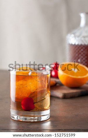 Classic old-fashioned cocktail with a cherry on a wooden table
