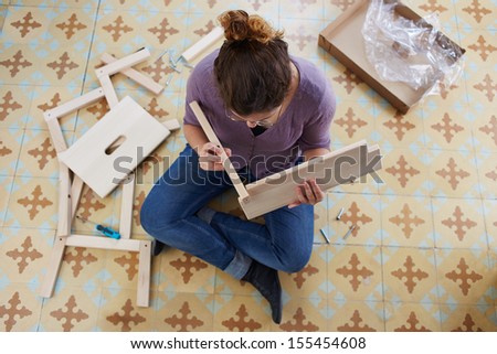 Young woman trying to assemble a piece of furniture