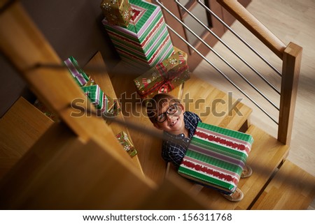 Smiling boy ready to open Christmas presents on the stairs of his house
