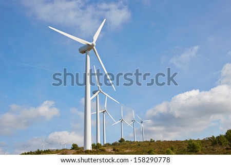 Group of windmills for renewable electric energy production on blue sky