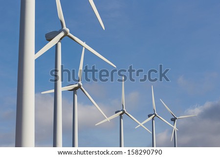 Group of windmills for renewable electric energy production on blue sky