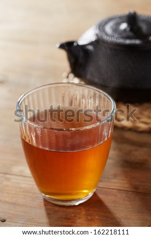 Brown tea on glass cup with black iron tea maker