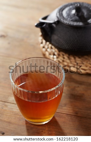 Brown tea on glass cup with black iron tea maker
