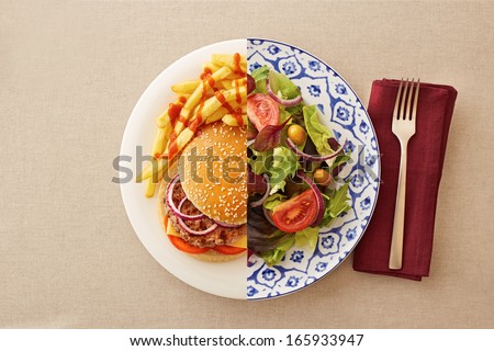Low fat healthy salad against unhealthy greasy burger Low fat healthy salad against unhealthy greasy burger