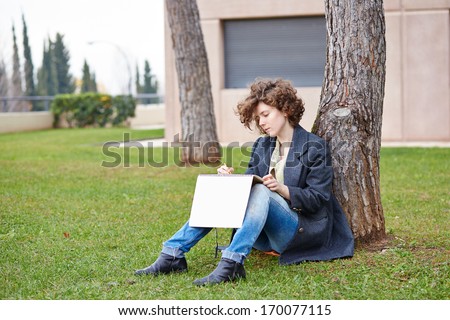 Female redhead art student drawing outdoors at college campus