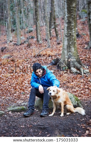Young Man Petting Dog On Winter Forest