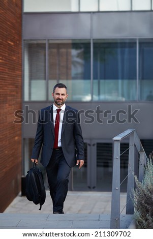 Businessman in a suit walking in front of office bulding