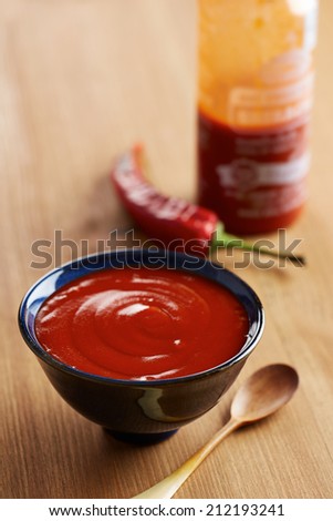 Bowl and bottle of sriracha sauce