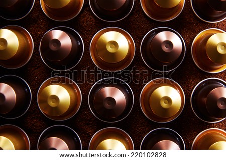 Gold and brown coffee capsules on coffee background