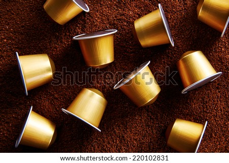 Fancy gold coffee capsules on coffee background