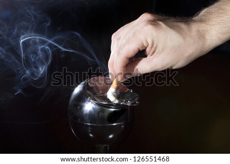 man\'s hand off cigarette in an ashtray