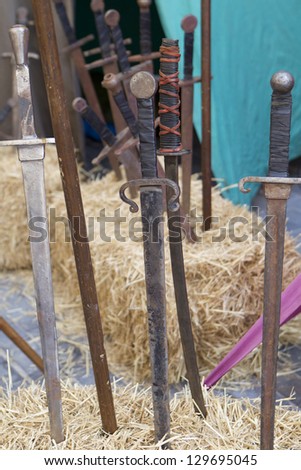 group of medieval swords stuck into straw bales