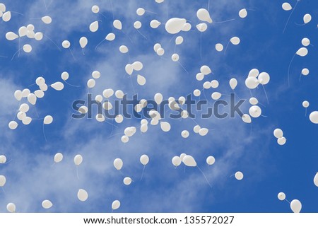group of white balloons flying in the sky