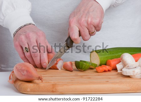 slicing vegetables on a wooden chopping board.