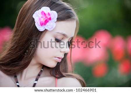 Portrait of teenage girl in profile with a delicate pink flower in her hair