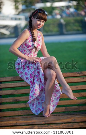 Picture a charming young girl posing in the park and shows her sexy bare legs