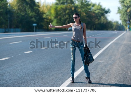 Photo slender young girl trying to stop the car on the road